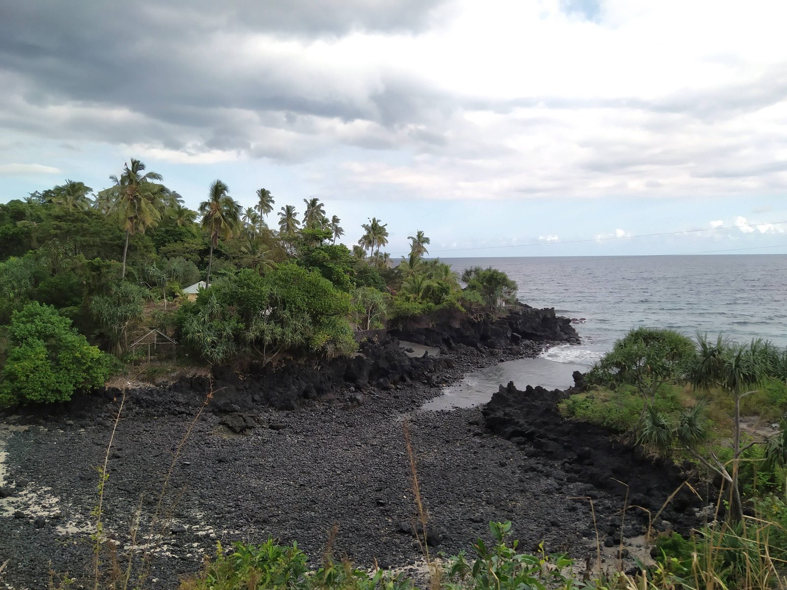 The volcanic shoreline of Grande Comore in the Comoros, with shallow reef water meeting a rocky coast